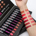Set of matte lipsticks with a hand swatching various shades on a white background